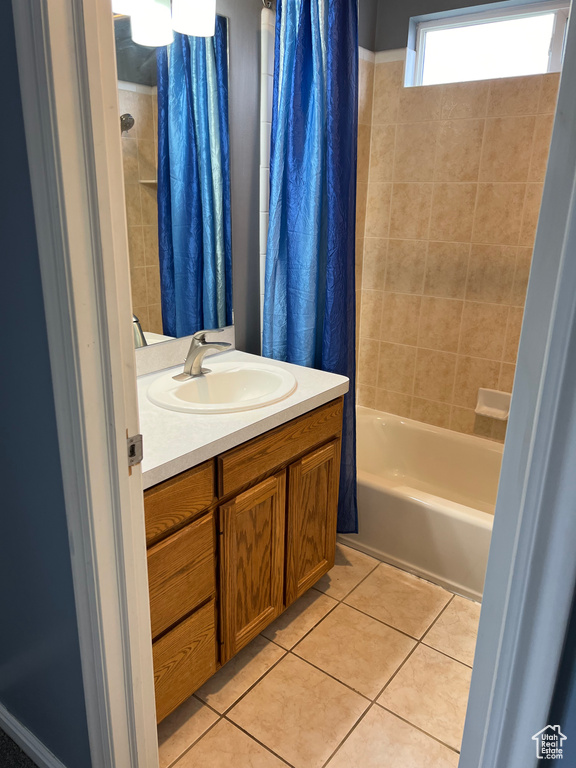 Bathroom with vanity with extensive cabinet space, shower / bathtub combination with curtain, and tile flooring