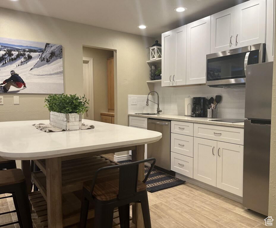 Kitchen with sink, light hardwood / wood-style floors, tasteful backsplash, and stainless steel appliances
