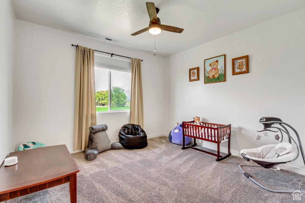 Bedroom featuring carpet, a nursery area, and ceiling fan