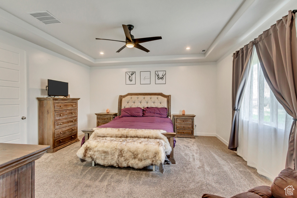 Bedroom with ceiling fan, a tray ceiling, and carpet floors