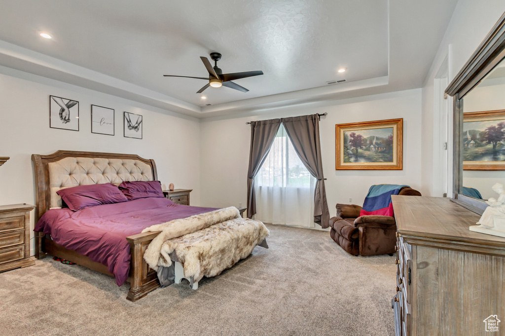 Bedroom featuring ceiling fan, a raised ceiling, and carpet floors