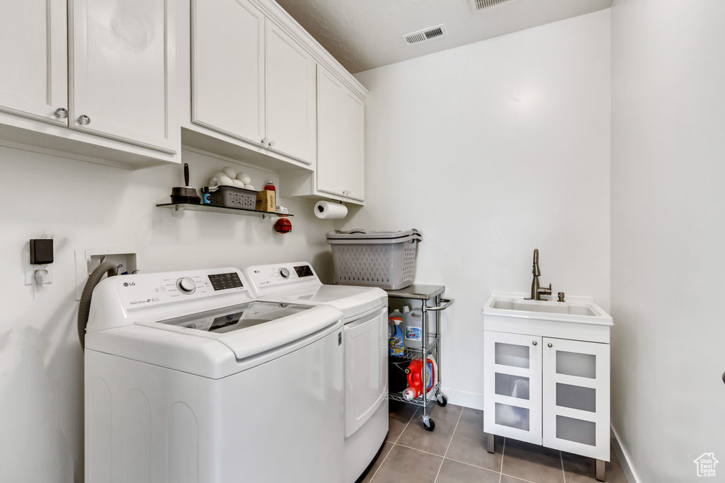 Laundry room with sink, cabinets, light tile floors, and separate washer and dryer