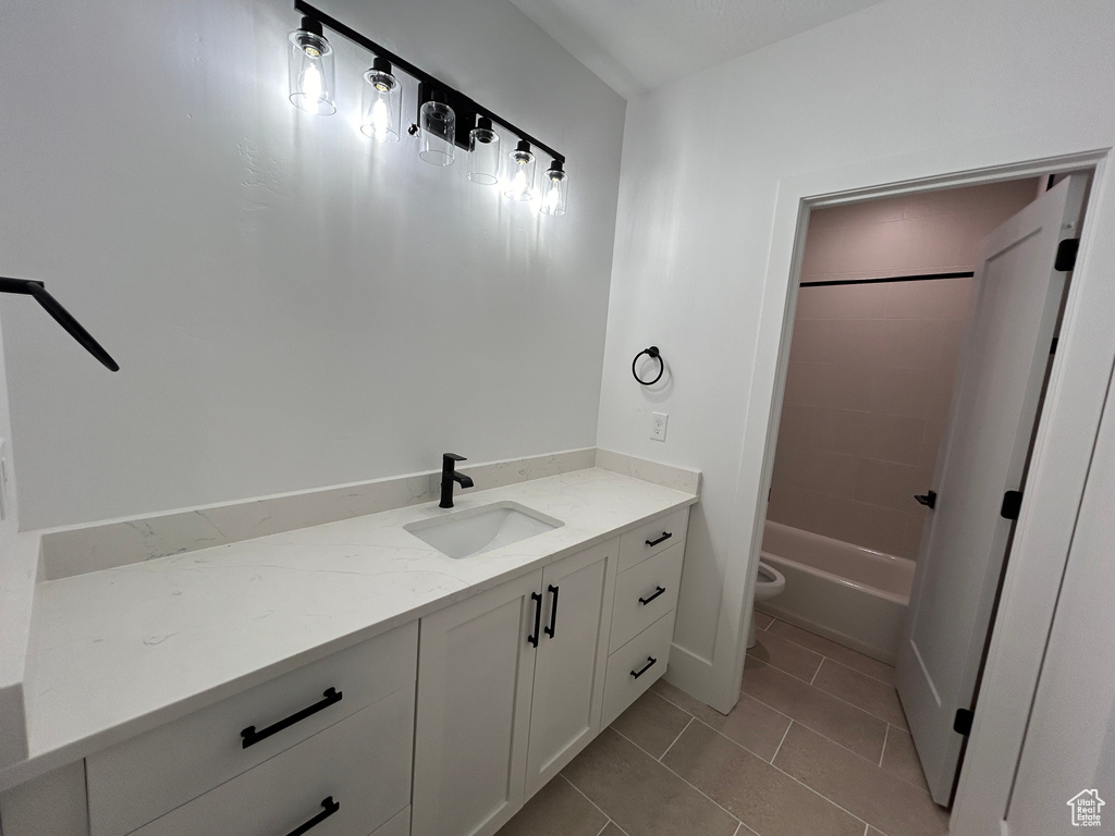 Full bathroom with toilet, tile floors, vanity, and washtub / shower combination
