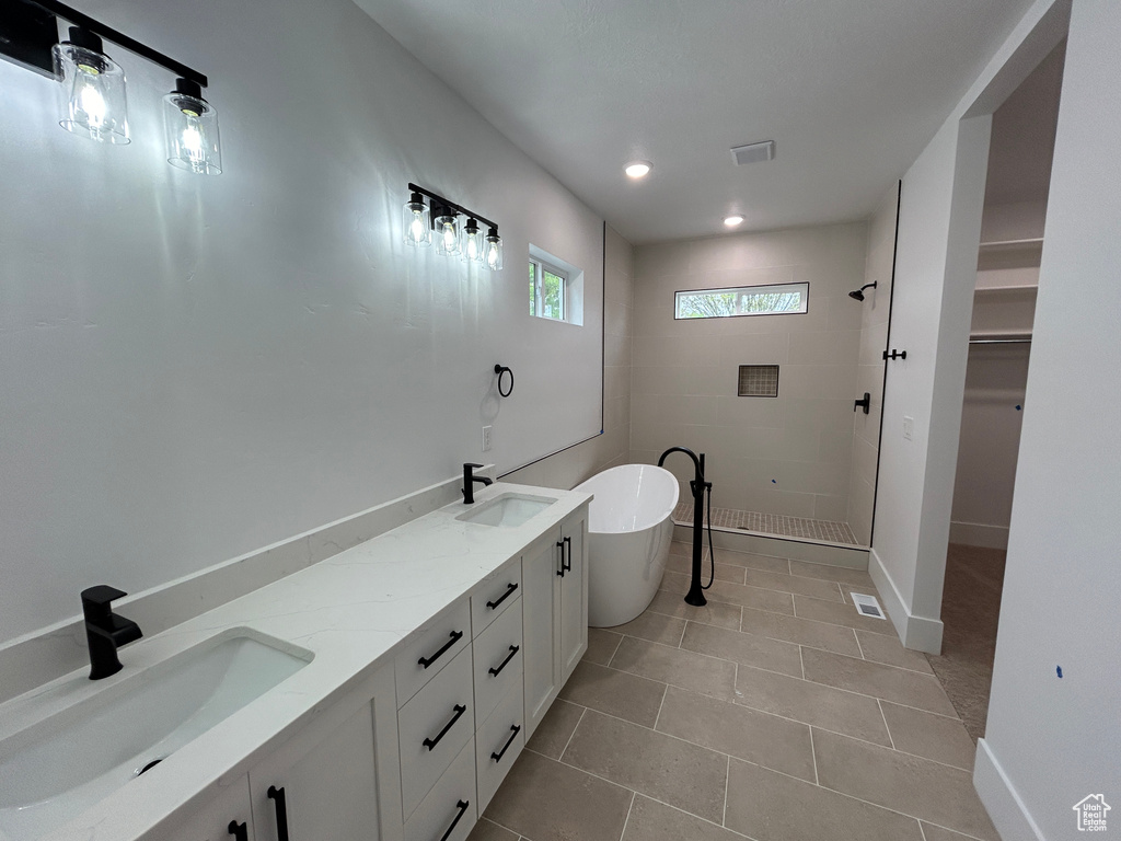 Bathroom with tile flooring, independent shower and bath, and double sink vanity