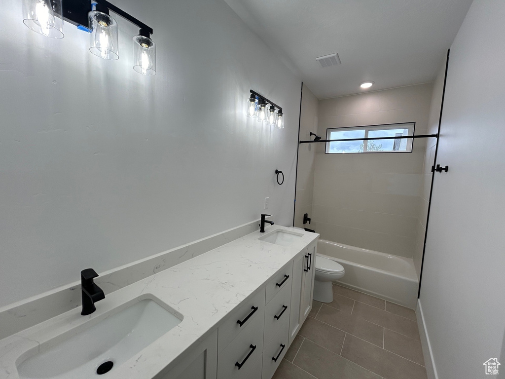 Full bathroom with tile flooring, washtub / shower combination, toilet, and dual vanity