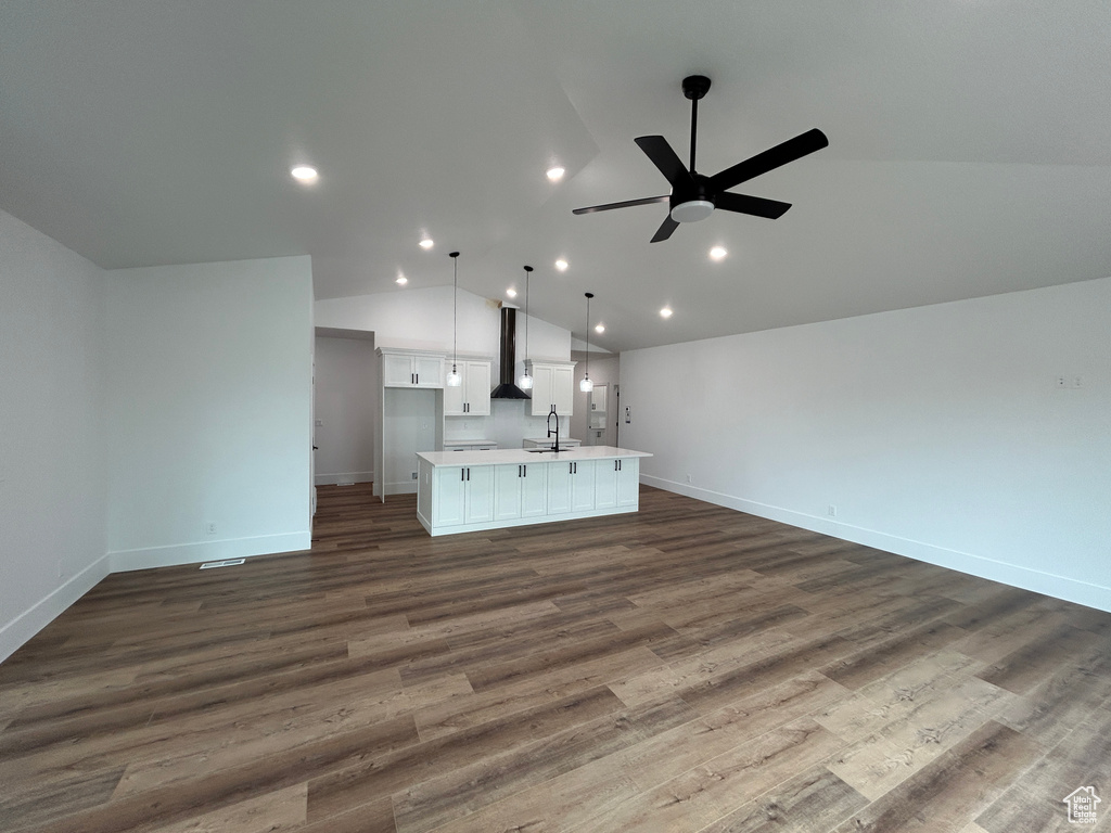 Unfurnished living room featuring hardwood / wood-style floors, vaulted ceiling, ceiling fan, and sink