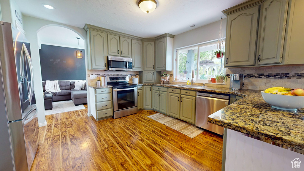 Kitchen featuring tasteful backsplash, light hardwood / wood-style floors, stainless steel appliances, and sink