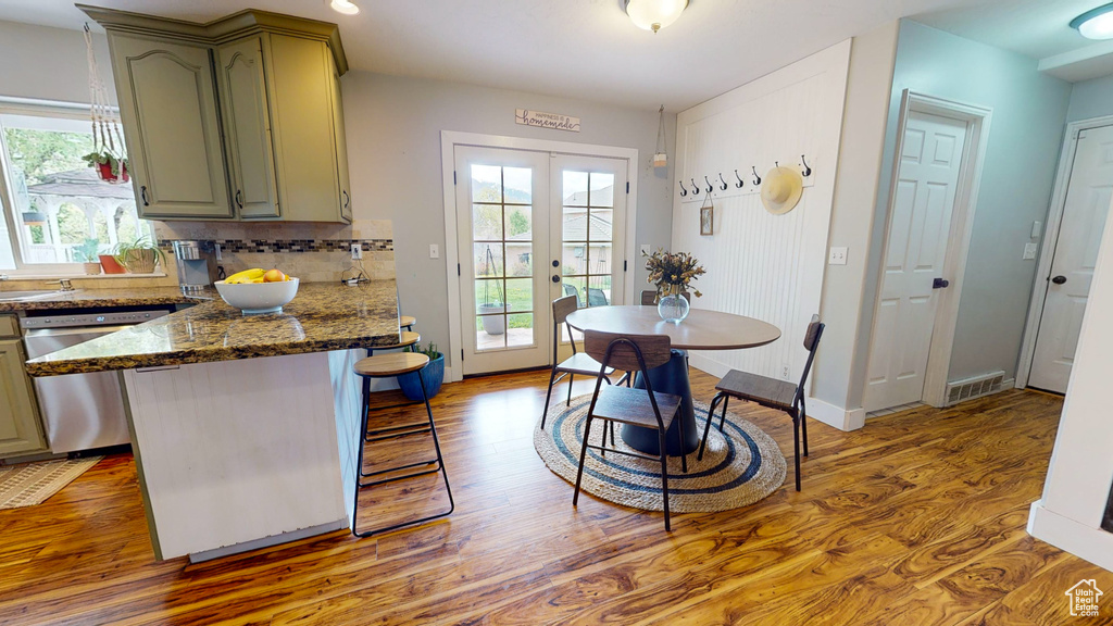 Kitchen featuring french doors, green cabinetry, dishwasher, tasteful backsplash, and hardwood / wood-style flooring