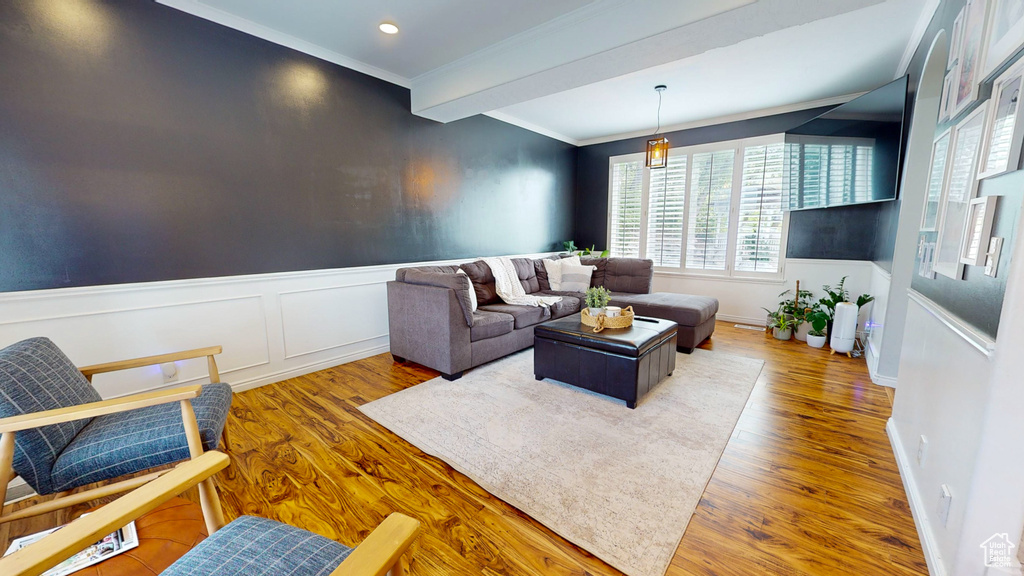 Living room featuring hardwood / wood-style floors, beamed ceiling, and crown molding