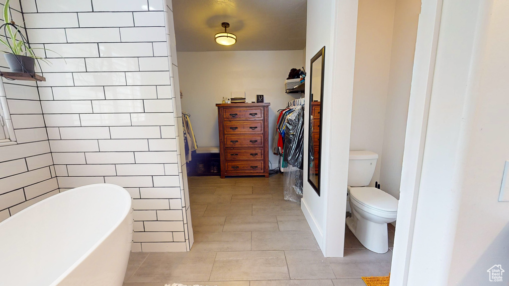 Bathroom featuring a bathing tub, toilet, and tile flooring