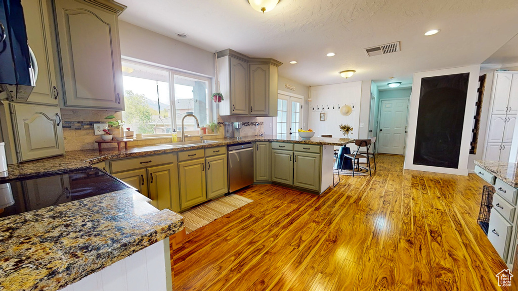 Kitchen with appliances with stainless steel finishes, light hardwood / wood-style flooring, tasteful backsplash, and kitchen peninsula