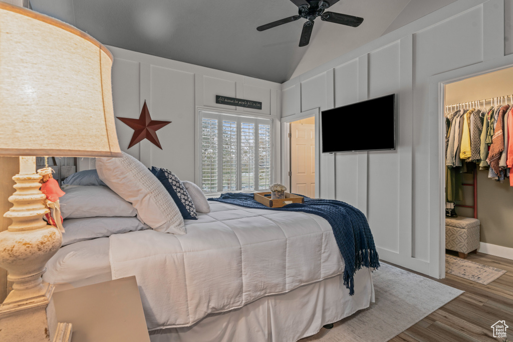Bedroom with a spacious closet, light hardwood / wood-style flooring, ceiling fan, lofted ceiling, and a closet