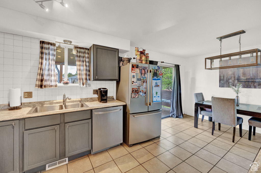 Kitchen with sink, light tile flooring, tasteful backsplash, stainless steel appliances, and pendant lighting