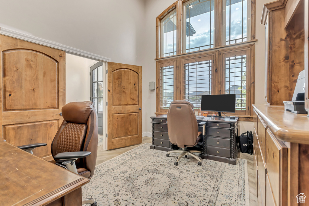 Office space featuring light hardwood / wood-style flooring and a high ceiling
