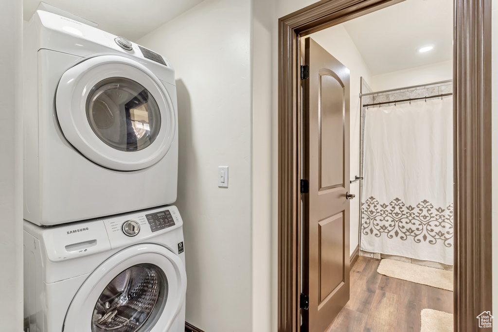 Clothes washing area featuring stacked washer and dryer and dark hardwood / wood-style floors