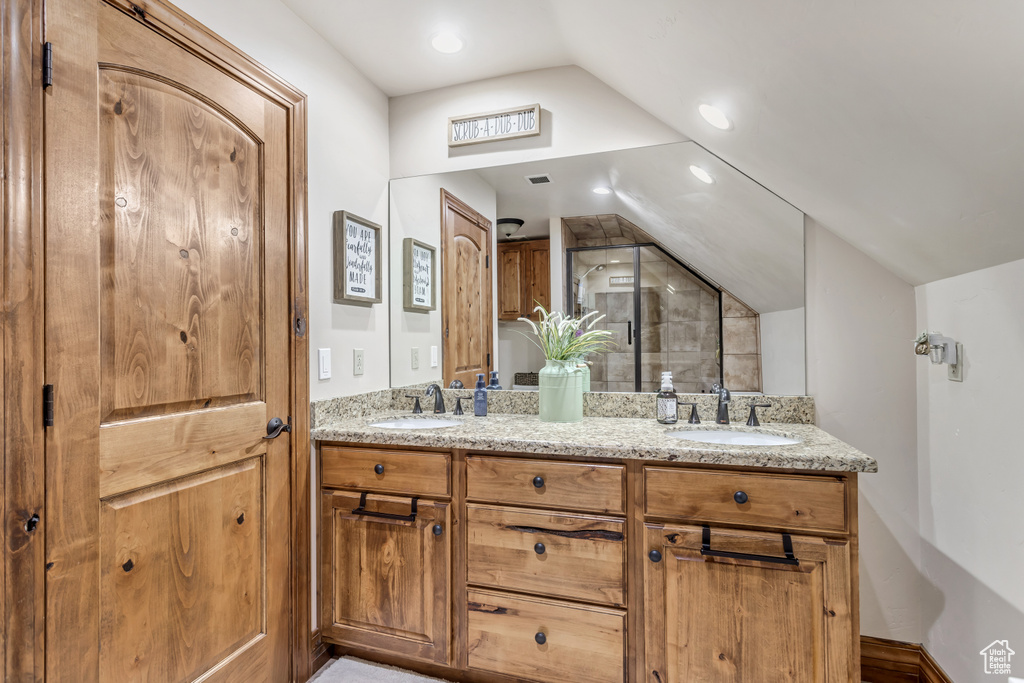 Bathroom with vaulted ceiling, vanity with extensive cabinet space, and double sink