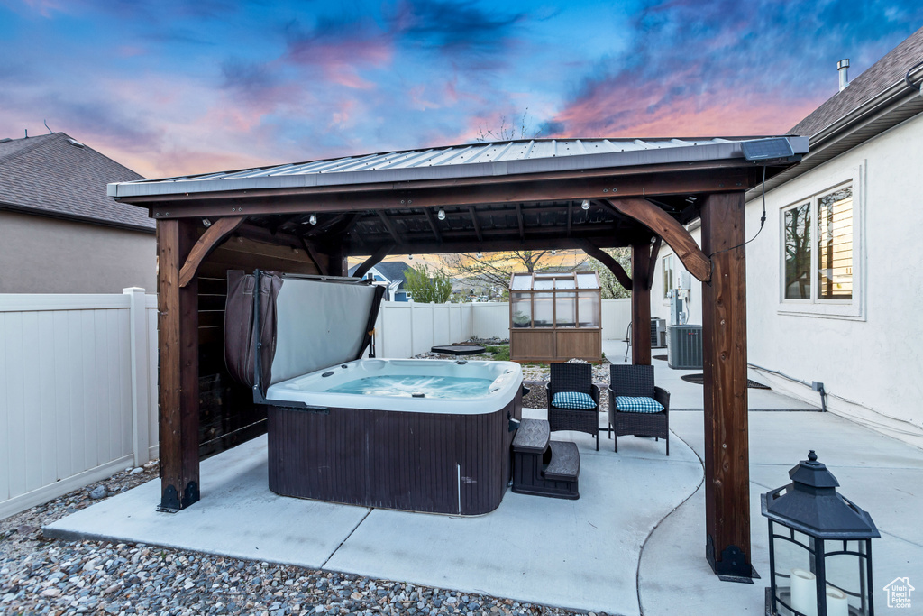 Patio terrace at dusk with a gazebo and a hot tub