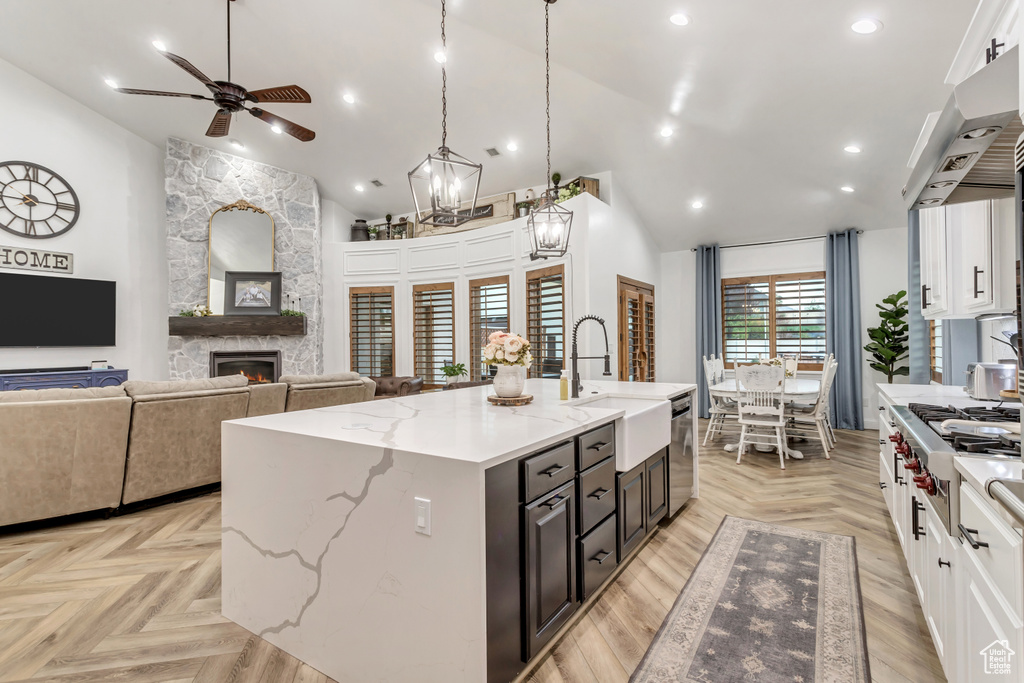 Kitchen with white cabinets, light parquet floors, ceiling fan, and a kitchen island with sink