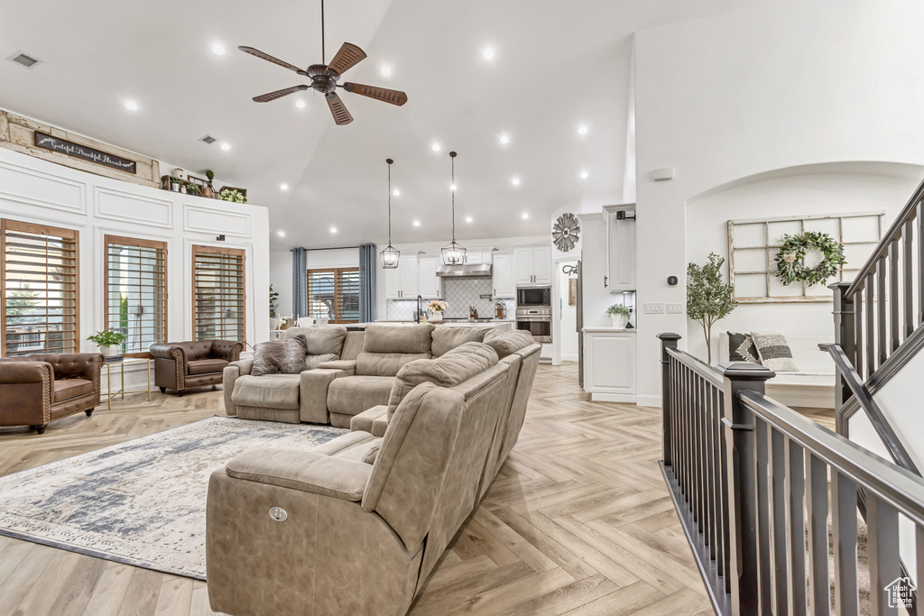 Living room featuring ceiling fan, high vaulted ceiling, and light parquet flooring