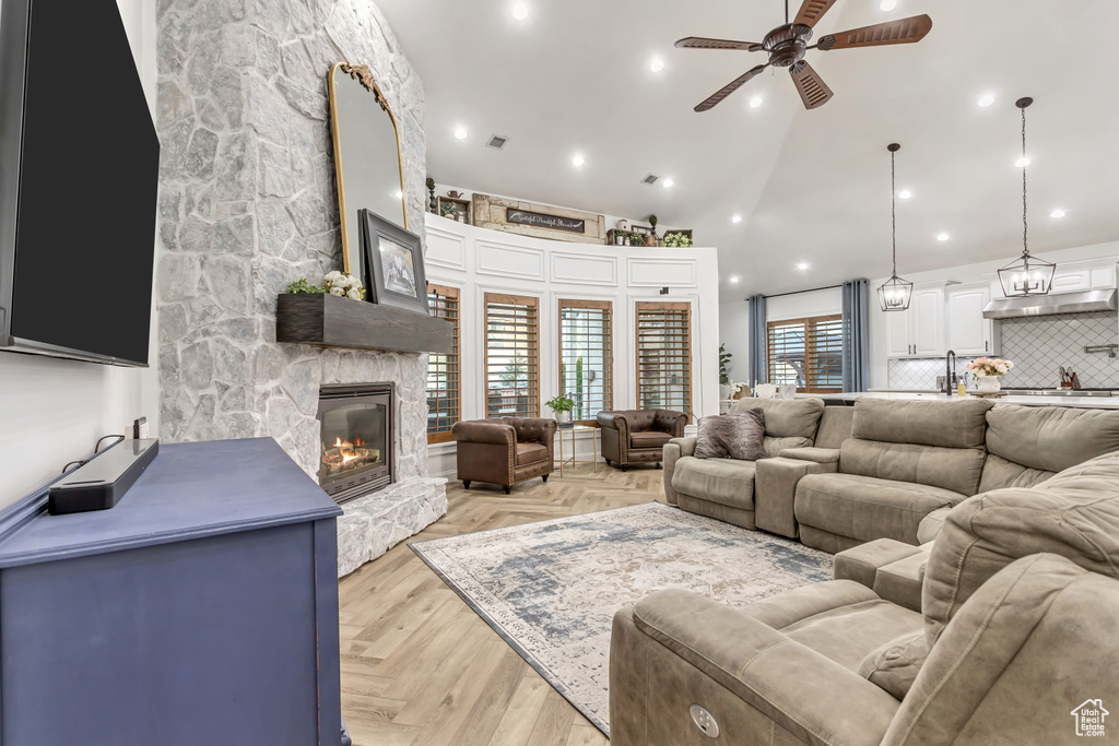 Living room with a stone fireplace, high vaulted ceiling, and ceiling fan