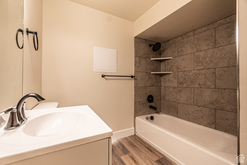 Full bathroom featuring wood-type flooring, vanity, toilet, and tiled shower / bath combo