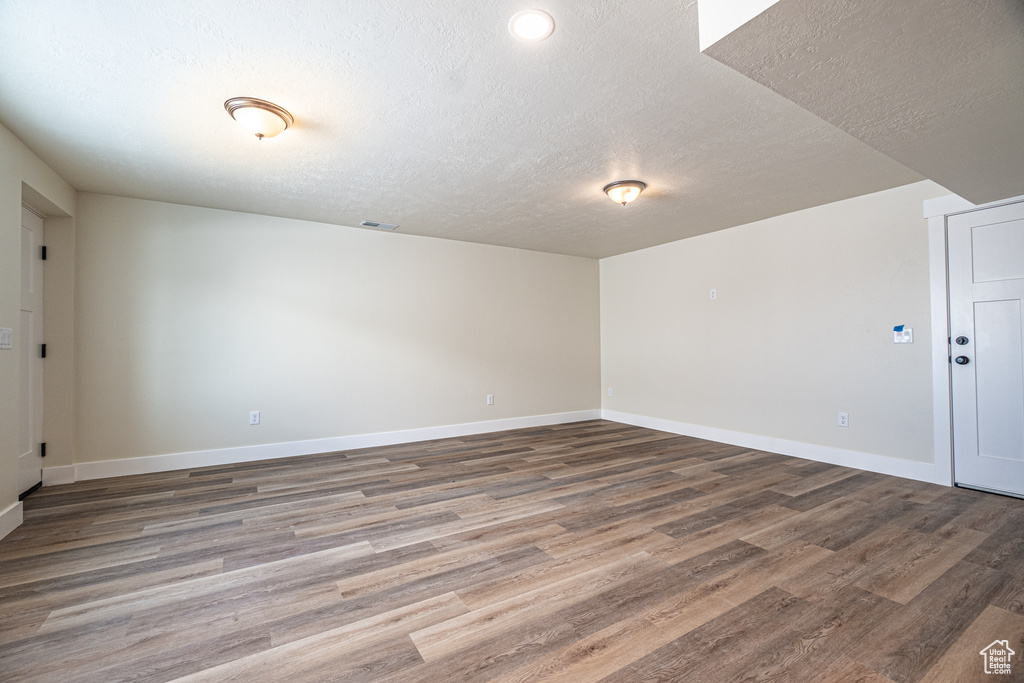 Unfurnished room featuring hardwood / wood-style flooring and a textured ceiling