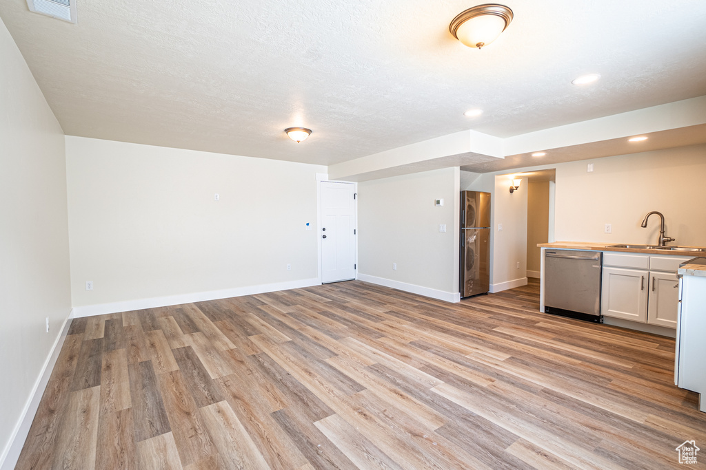 Basement featuring sink, light hardwood / wood-style floors, and stainless steel refrigerator