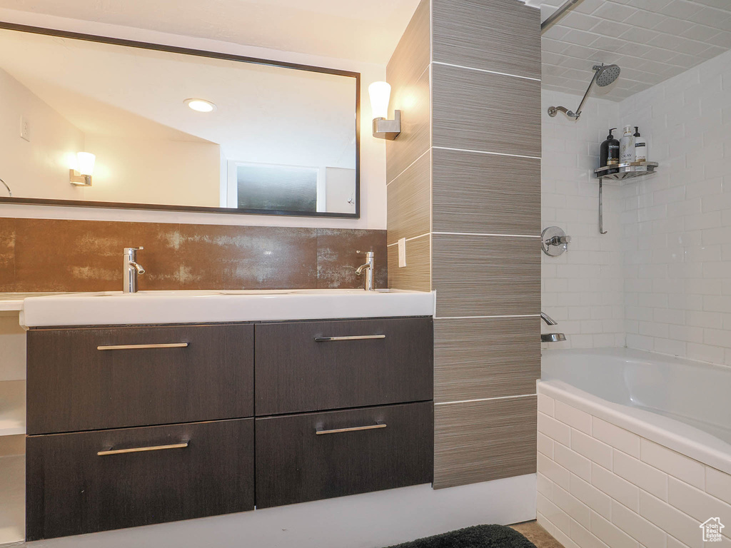 Bathroom with vanity with extensive cabinet space and tiled shower / bath