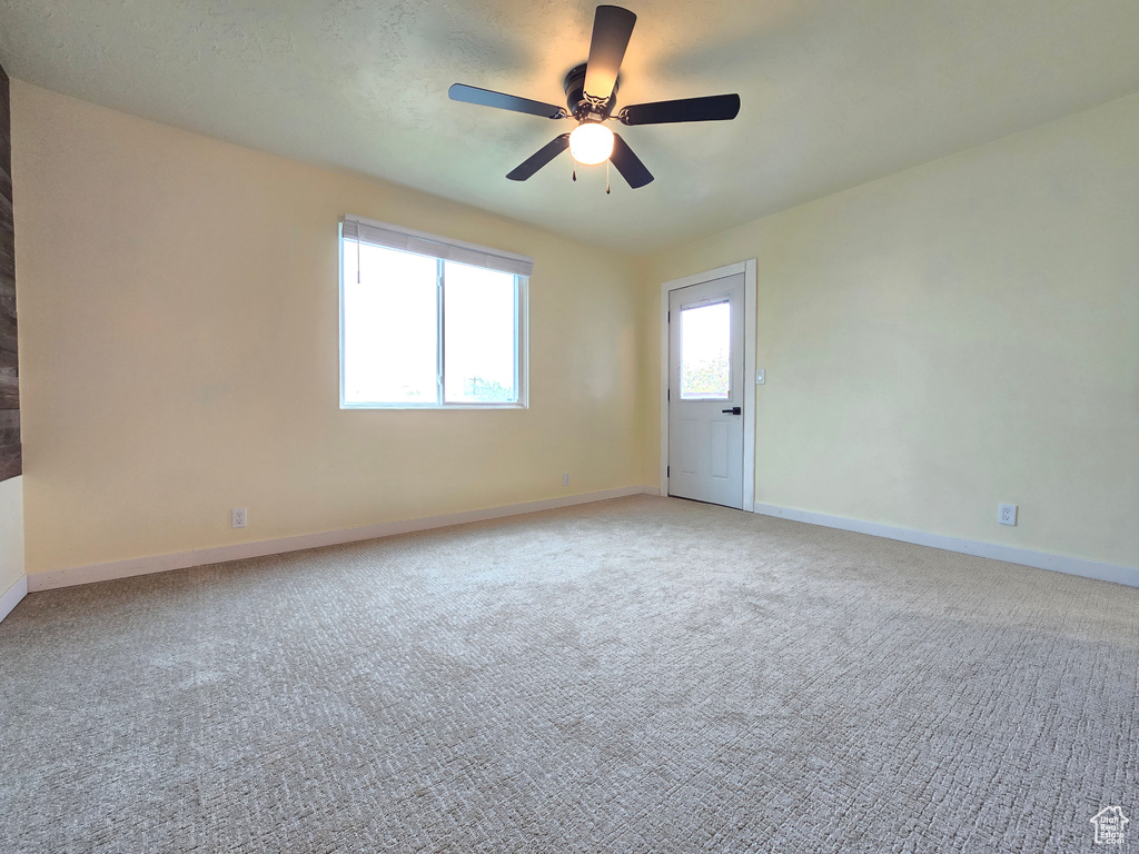 Carpeted empty room featuring ceiling fan and a healthy amount of sunlight