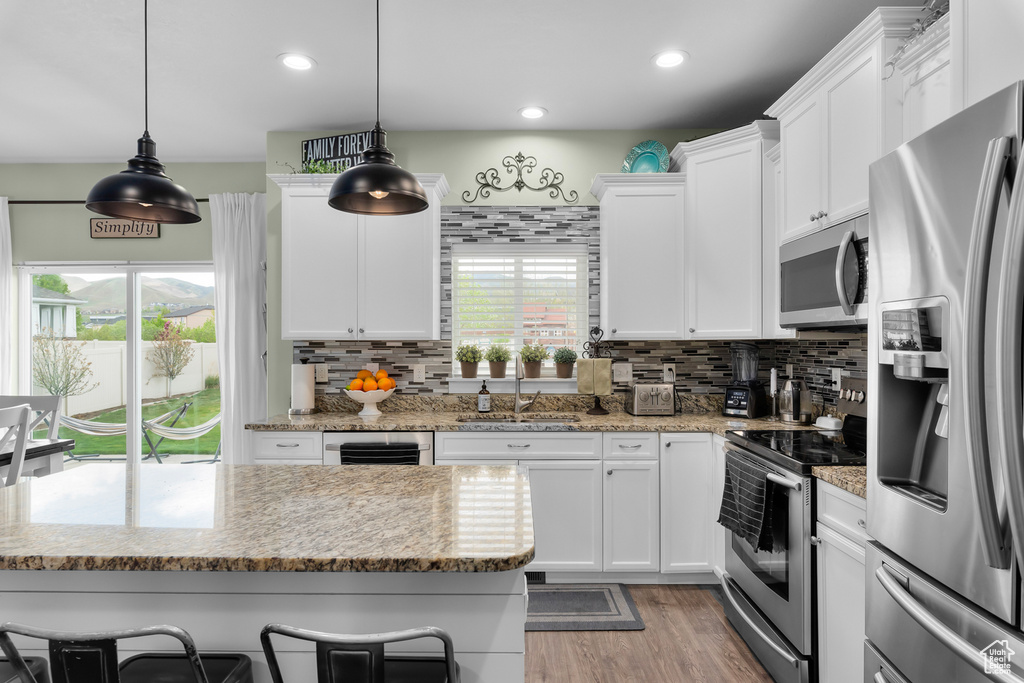Kitchen with tasteful backsplash, stainless steel appliances, sink, and light wood-type flooring