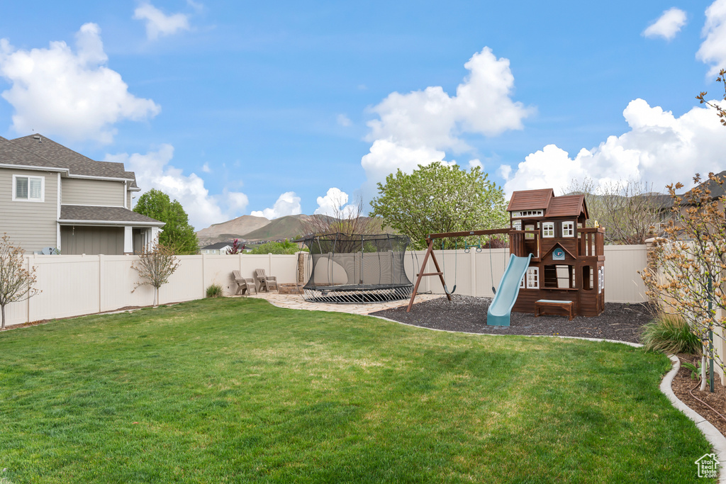 View of yard with a mountain view, a playground, and a trampoline