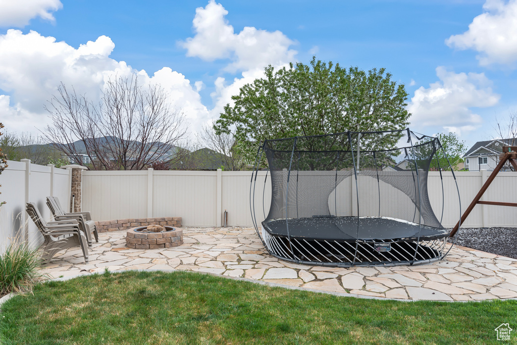 View of yard with a patio, an outdoor fire pit, and a trampoline