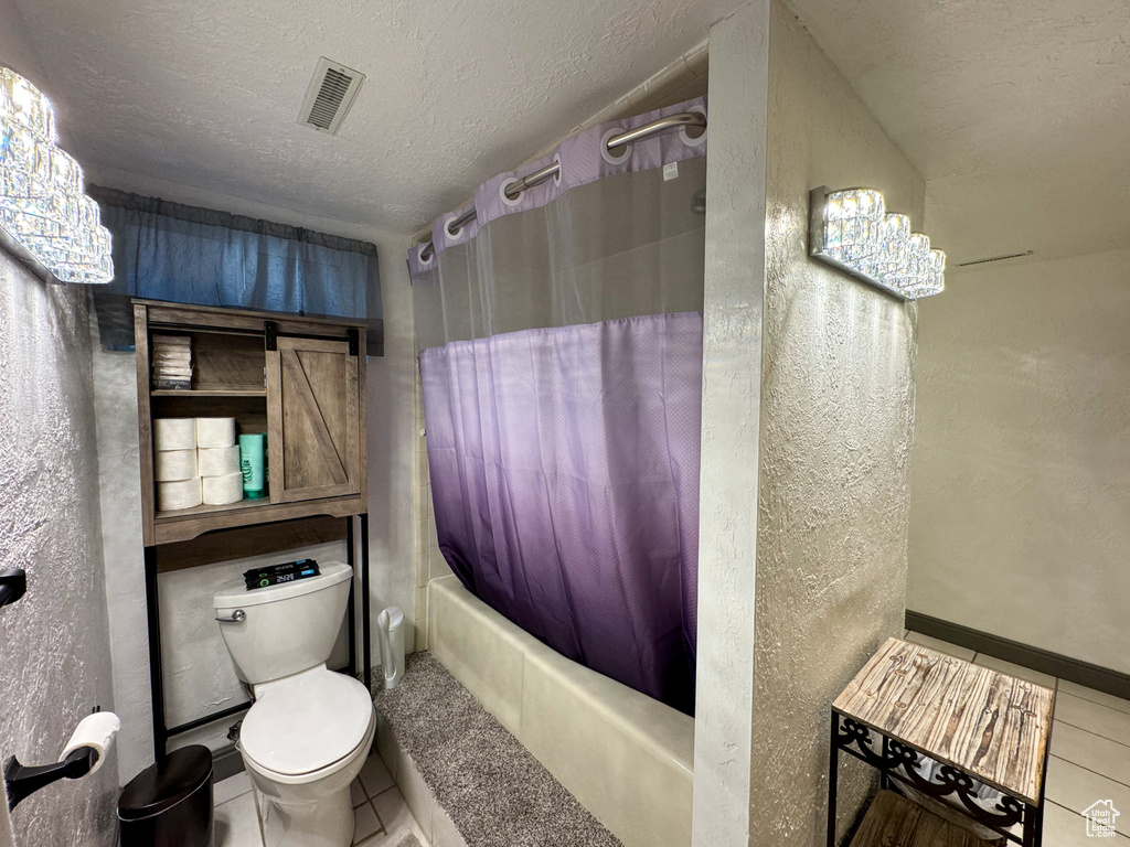 Bathroom with tile flooring, shower / tub combo, toilet, and a textured ceiling