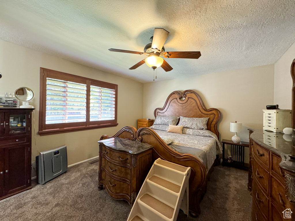 Bedroom featuring dark colored carpet, ceiling fan, and a textured ceiling