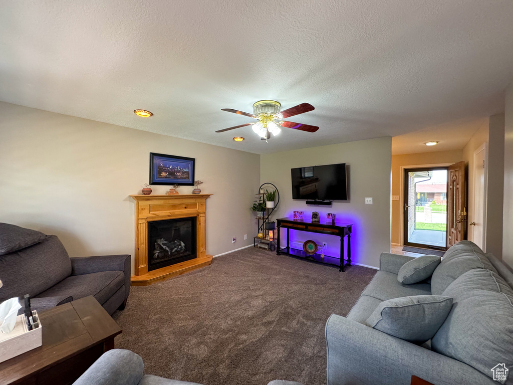 Living room with dark carpet, ceiling fan, and a textured ceiling