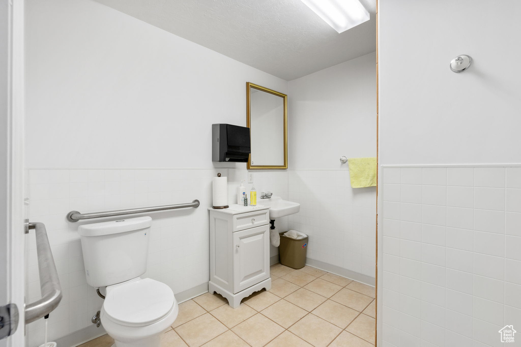 Bathroom with tile walls, toilet, tile floors, and vanity