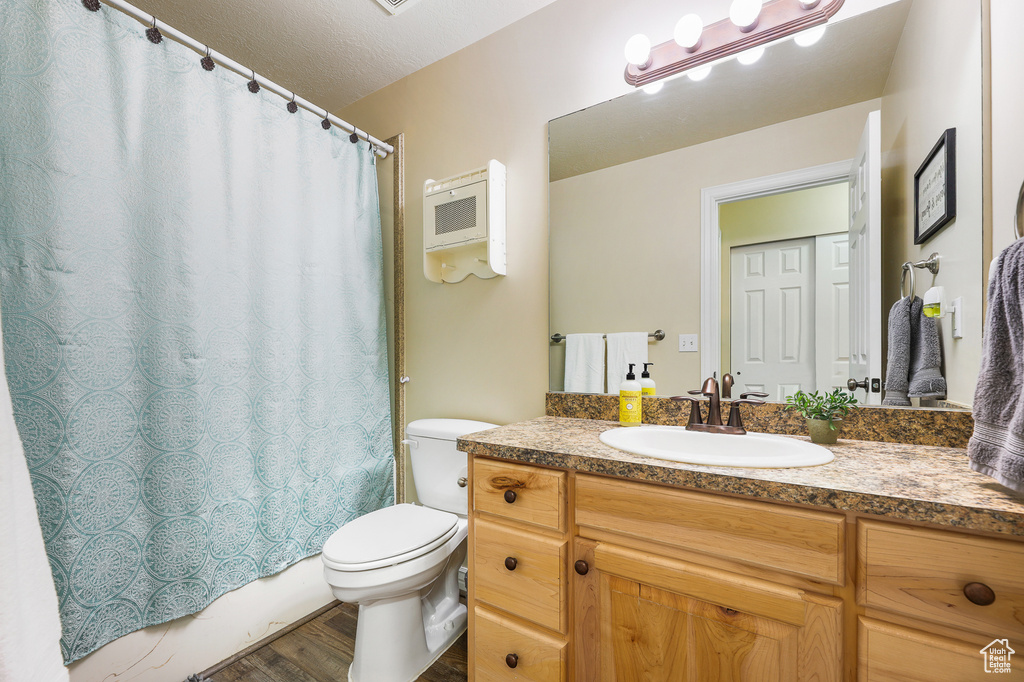 Full bathroom with shower / tub combo with curtain, hardwood / wood-style flooring, toilet, and large vanity