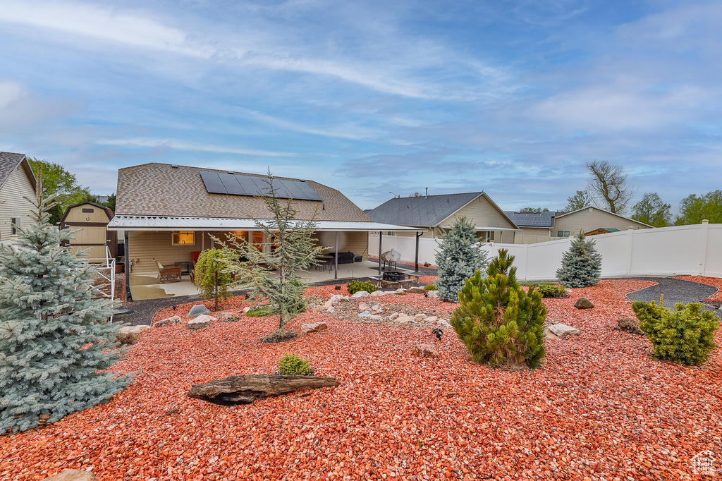 Rear view of property with solar panels and a patio