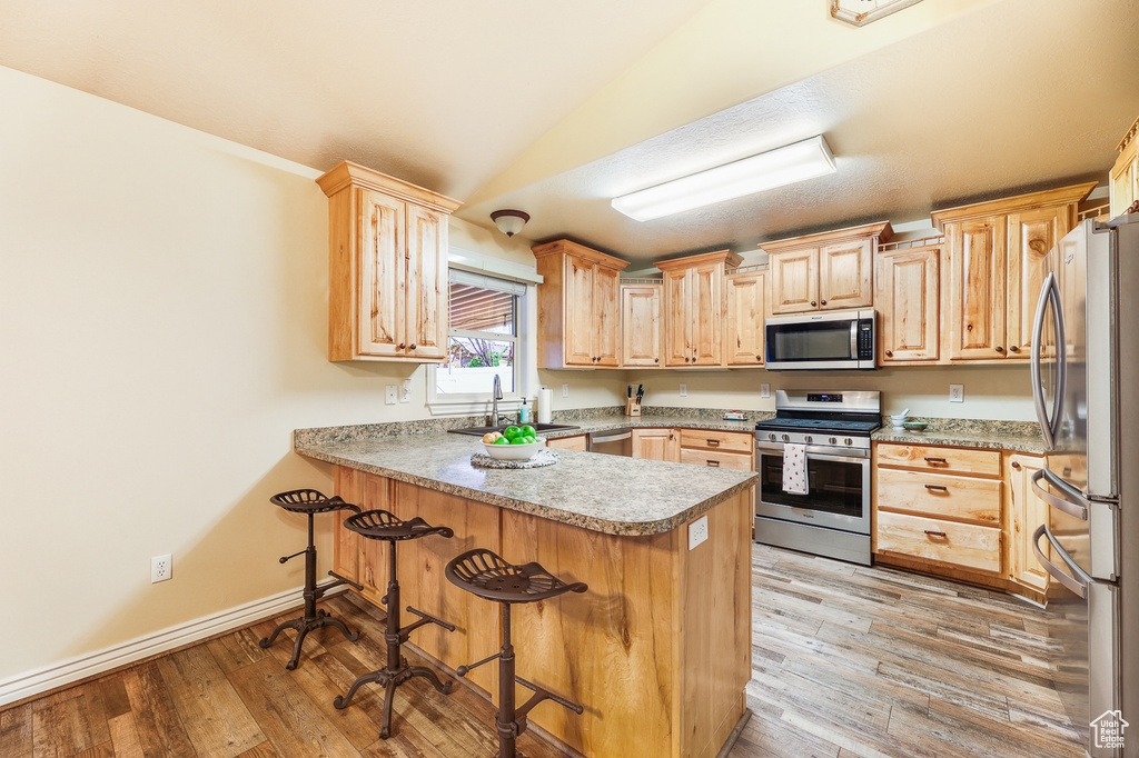 Kitchen with light brown cabinets, light hardwood / wood-style flooring, stainless steel appliances, and sink