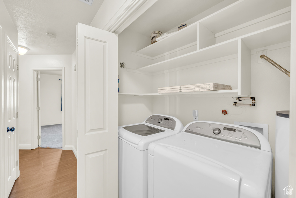 Laundry room with light wood-type flooring and washing machine and clothes dryer