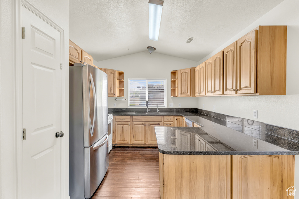 Kitchen with sink, stainless steel fridge, dark hardwood / wood-style floors, vaulted ceiling, and kitchen peninsula