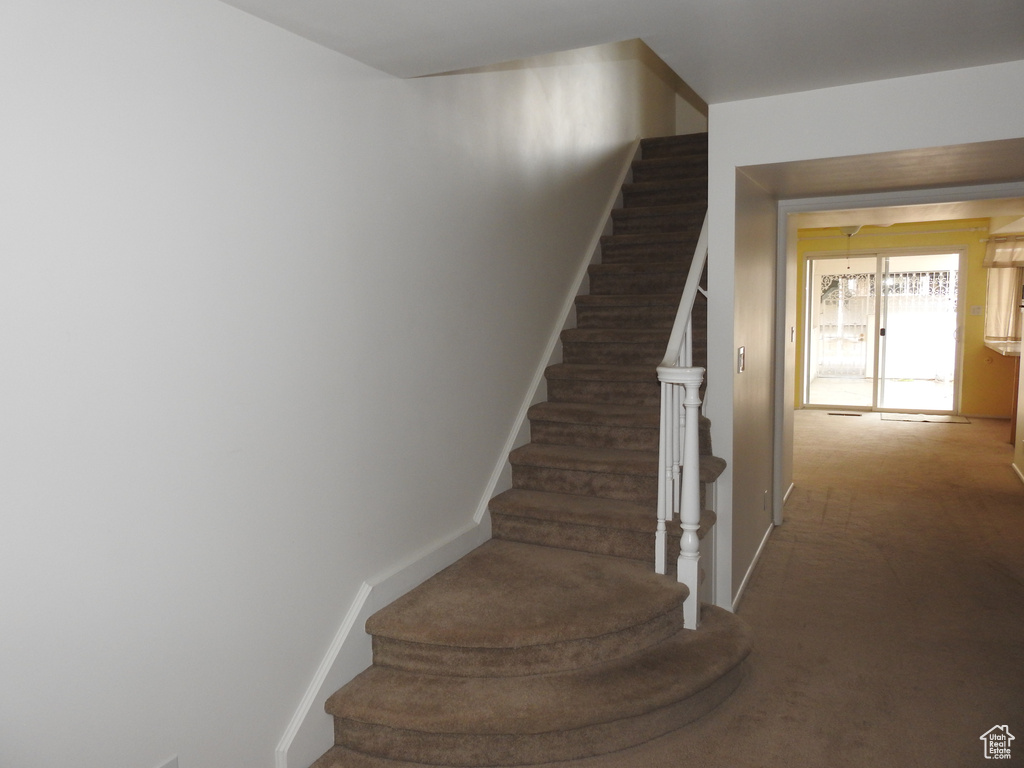 Stairway featuring dark colored carpet