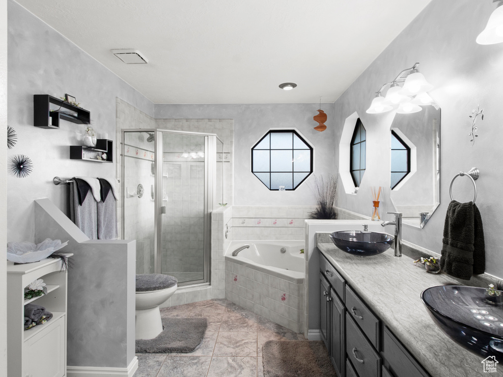 Full bathroom with large vanity, toilet, shower with separate bathtub, tile floors, and dual sinks
