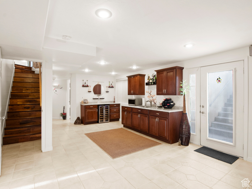 Kitchen with sink, wine cooler, dark brown cabinets, and light tile floors