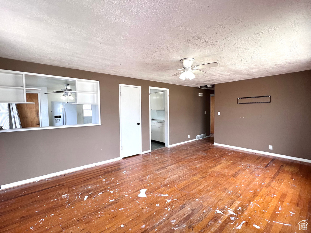 Empty room with hardwood / wood-style flooring, ceiling fan, and a textured ceiling