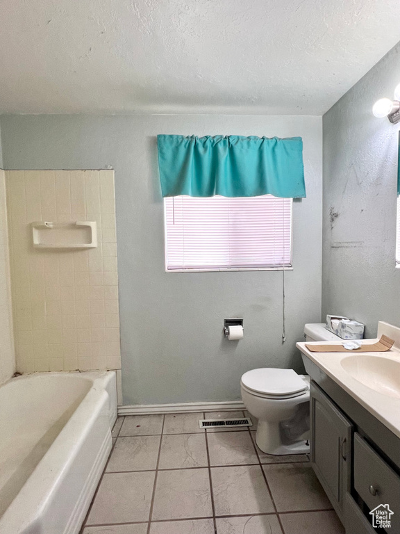 Bathroom featuring vanity, toilet, tile floors, and a textured ceiling