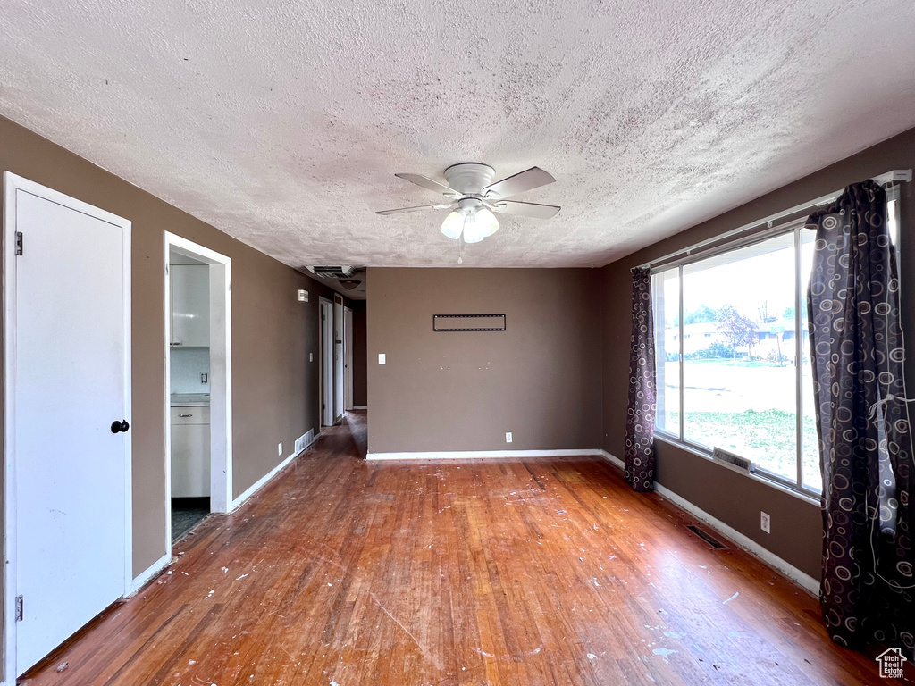 Empty room featuring a textured ceiling, ceiling fan, and hardwood / wood-style flooring