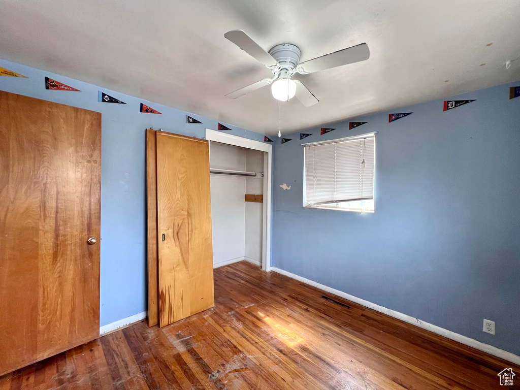 Unfurnished bedroom featuring a closet, dark hardwood / wood-style flooring, and ceiling fan