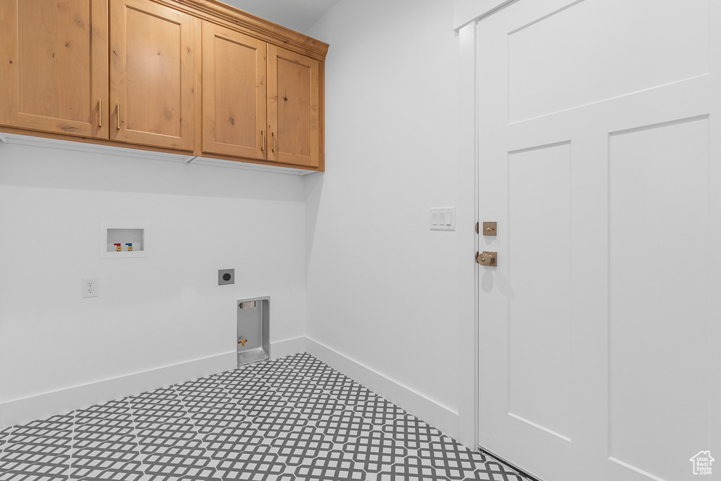 Clothes washing area featuring hookup for an electric dryer, washer hookup, baseboards, cabinet space, and tile patterned floors