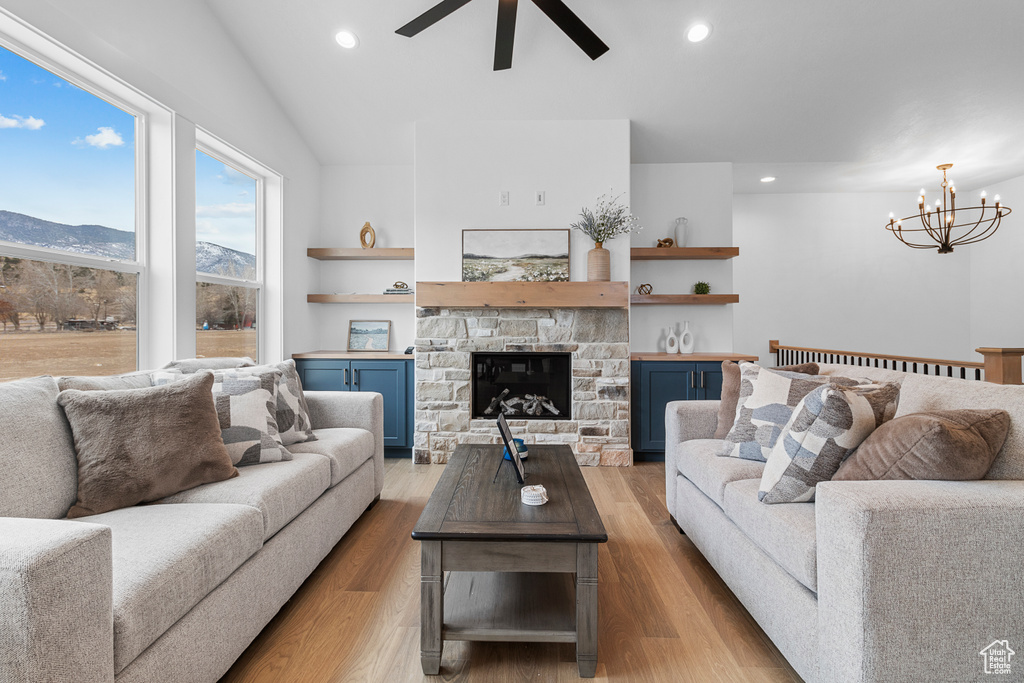 Living area featuring ceiling fan with notable chandelier, recessed lighting, a stone fireplace, and wood finished floors